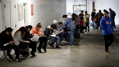 In this March 13, 2020 file photo, unionized hospitality workers wait in line in a basement garage to apply for unemployment benefits at the Hospitality Training Academy in Los Angeles. More than 6.6 million Americans applied for unemployment benefits last week, far exceeding a record high set just last week, a sign that layoffs are accelerating in the midst of the coronavirus.