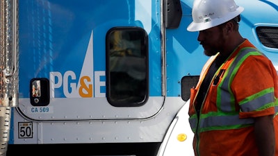 In this Aug. 15, 2019, file photo, a Pacific Gas & Electric worker walks in front of a truck in San Francisco.