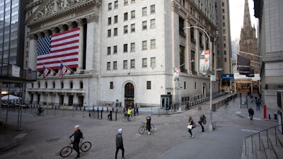 In this March 18, 2020, file photo a few people walk on Wall Street in front of the New York Stock Exchange in New York. There are emerging signs that any recovery will fail to match the speed and severity of the economic collapse that occurred in just a few weeks.