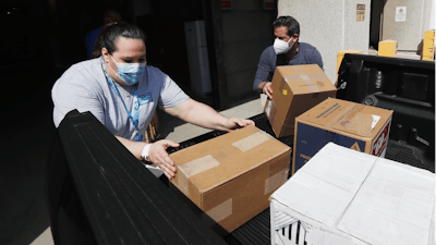 Christina Caldwell, left, of Henry Ford Population Health helps unload supplies with Matt Thatcher, who donated them from the Detroit Golf Club, Wednesday, April 8, 2020, in Detroit. The hospital is also in need of gowns and other PPE items and hopes more donations will be coming in from others to help during the coronavirus pandemic.