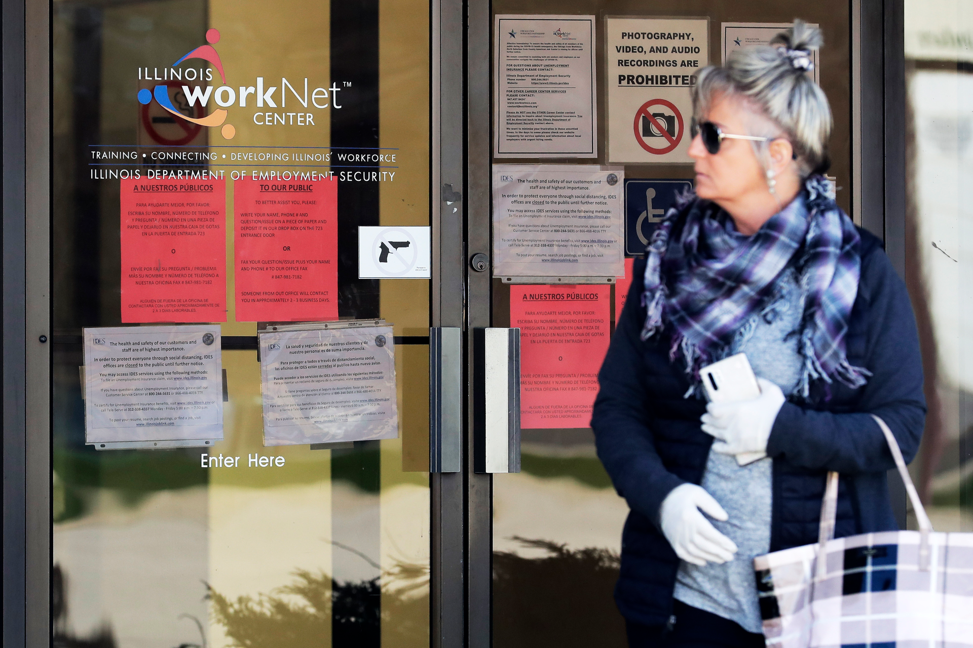 A woman looks to get information about job application in front of IDES (Illinois Department of Employment Security) WorkNet center in Arlington Heights, Ill., Thursday, April 9, 2020. Another 6.6 million people filed for unemployment benefits last week, according to the US Department of Labor, as American workers continue to suffer from devastating job losses, furloughs and reduced hours during the coronavirus pandemic.