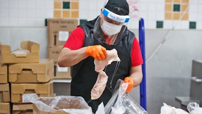 Amid concerns of the spread of COVID-19, Giovani Garcia sorts chicken at the butcher area of El Rancho grocery store in Dallas, Monday, April 13, 2020.