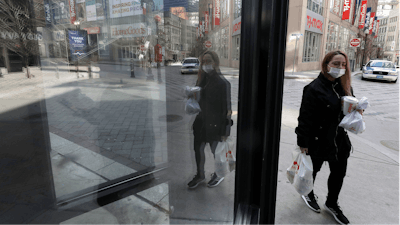 A passerby walks past an entrance to a closed store in the nearly empty Downtown Crossing neighborhood, Tuesday, April, 14, 2020, in Boston.