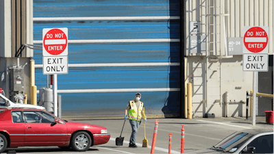 In this April 13, 2020 file photo, a worker wears a mask as he cleans up an area outside an entrance at Boeing Co.'s airplane assembly facility in Everett, Wash., north of Seattle.