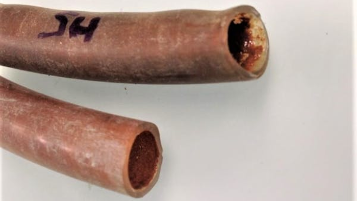 Cut-open shower pipes reveal a biofilm with metal deposits.