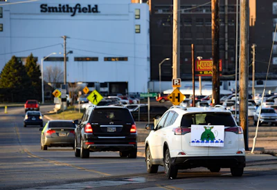 In this April 9 photo, a sign depicting Smithfield Food, Inc. as a pig-shaped money bag is visible on the back of a car during a protest on behalf of employees calling for a safe and healthy workplace drives past Smithfield Foods, Inc. in Sioux Falls, SD.