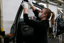 An employee wearing a face mask works on a door of a Yaris car at the Toyota car factory in Onnaing, France, April 28, 2020.