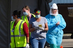 In this Saturday, April 18, 2020, photo, medical workers administer drive-up COVID-19 tests outside the Sanford Worthington Clinic in Worthington, Minn. The state has sent a team to ensure safe conditions in the southwestern Minnesota city, where multiple people have tested positive at a meatpacking plant.