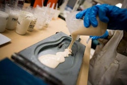 A student pouring polyurethane into a flip-flop mold.