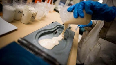 Image from the research team's prior work, showing a student pouring polyurethane into a flip-flop mold.