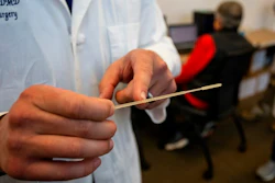 In this Tuesday, April 28, 2020, photo, Alexander Faigen, of Augusta University's Dental College of Georgia, shows how far a nasal swab must be inserted in Augusta, Ga. Volunteers at a Georgia dental college who started using a 3D printer to make nasal swabs used in test kits for the coronavirus are now a major part of the state's effort to expand testing.