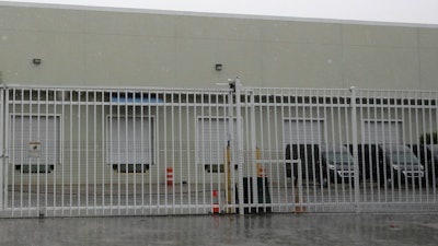 This Thursday, April 30, 2020 photo shows the gate outside a warehouse in Weston, Fla. used by the U.S. Drug Enforcement Agency.