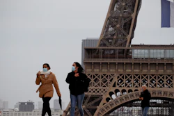 People walk near the Eiffel Tower, in Paris, Monday, May 11, 2020.