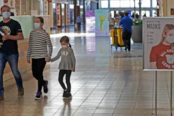 Shoppers walks past a sign encouraging masks at SouthPark Mall, Wednesday, May 13 in Strongsville, OH.