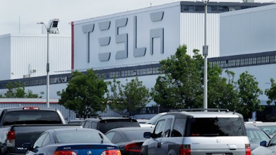This photo shows vehicles in the parking lot of the Tesla electric car plant Wednesday, May 13, 2020, in Fremont, Calif.