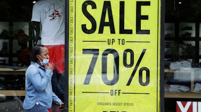 A woman walks past a store advertising sales at 70 percent off.