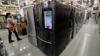 In this Jan. 27, 2020 file photo, a worker pushes a cart past refrigerators at a Home Depot store location in Boston.