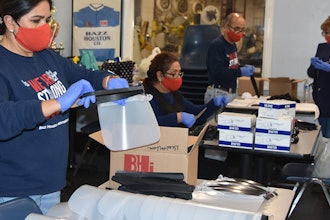 Workers and volunteers at Bazz Houston International assemble face shields.