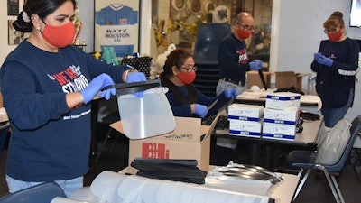 Workers and volunteers at Bazz Houston International assemble face shields.