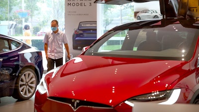 A customer wearing a face mask looks at automobiles in a Tesla car showroom in Beijing.