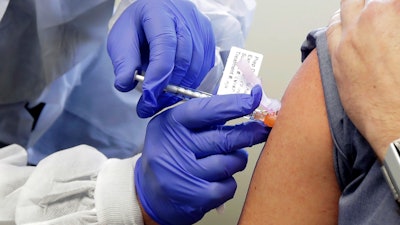 In this March 16, 2020, file photo, Neal Browning receives a shot in the first-stage safety study clinical trial of a potential vaccine for COVID-19, the disease caused by the new coronavirus, at the Kaiser Permanente Washington Health Research Institute in Seattle.