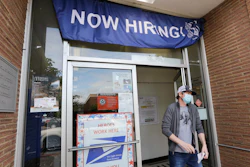 A customer walks out of a U.S. Post Office branch advertising a job opening, Seattle, June 4, 2020.