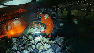 A firefighter puts out fire in the aftermath of a tanker truck explosion that damaged buildings near a highway in Wenling in eastern China's Zhejiang province Saturday, June 13, 2020. More than a dozen were killed and others injured after the tanker truck veered off the Shenyang-Haikou Expressway after the explosion.