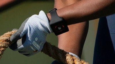 A tugboat deckhand demonstrates a digital bracelet that flashes red when a coworker is too close to him.