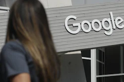 A woman walks below a Google sign on its campus in Mountain View, Calif., Sept. 24, 2019.