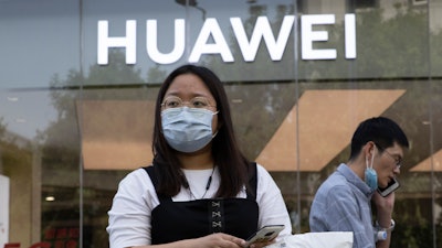 Residents wearing masks to curb the spread of the coronavirus past by a Huawei shop in Beijing.