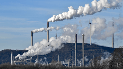 Uniper coal-fired power plant and BP refinery steam beside a wind generator in Gelsenkirchen, Germany.