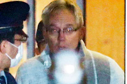 In this Dec. 25, 2018, file photo, then Nissan Motor Co.'s executive Greg Kelly, center, leaves Tokyo's Detention Center in Tokyo. Former Nissan executive Kelly, who was arrested in connection with the financial scandal of his ex-boss Carlos Ghosn, will soon face trial in a Tokyo court. Both cases had been in limbo after Ghosn fled to Lebanon. Tokyo Deputy Chief Prosecutor Hiroshi Yamamoto said Thursday, July 30, 2020, the trial of Kelly, an American, and Nissan Motor Co., a defendant in the same trial as a company, will start Sept. 15.