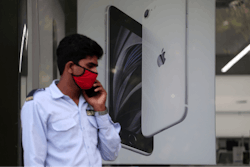 A security officer talks on a phone in front of an image of an iPhone displayed at an Apple store in Ahmedabad, India.