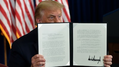 President Donald Trump signs an executive order during a news conference at the Trump National Golf Club.