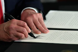 President Donald Trump signs an executive order during a news conference.