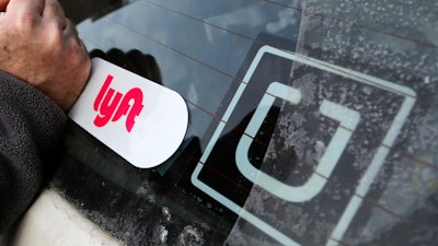 A Lyft logo is installed on a Lyft driver's car next to an Uber sticker.
