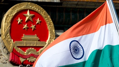 An Indian flag is flown next to the Chinese national emblem outside the Great Hall of the People, Beijing, Oct. 23, 2013.