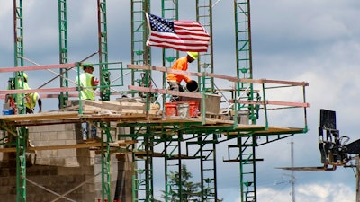 Workers on scaffolding lay blocks.