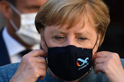 German Chancellor Angela Merkel takes her mask off as she arrives with French President Emmanuel Macron for a press conference at the Fort de Bregancon, France, Aug. 20, 2020.