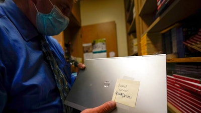 Tom Baumgarten, superintendent of the Morongo Unified School District, looks at a laptop with a cracked screen at Twentynine Palms Junior High School, Tuesday, Aug. 18, 2020, in Twentynine Palms, Calif. Baumgarten was set to order 5,000 Lenovo Chromebooks in July when his vendor called him off, saying Lenovos were getting 'stopped by a government agency because of a component from China that's not allowed here,' he said.