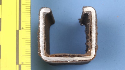 In this photo taken June 19, 2018, a cross-section of strut 16 from the Pennsylvania Turnpike Lehigh Tunnel no. 2 shows oxidation and PVC disbondment from the metal. The strut and other conduit support system and electrical conduit components were examined by the NTSB Materials Laboratory.