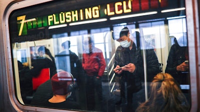 In this April 7, 2020, file photo, some people wear masks while using the New York City subway system during the coronavirus pandemic in New York. New York's mass transit agency wants Apple to come up with a better way for iPhone users to unlock their phones without taking off their masks, as it seeks to guard against the spread of COVID-19 in buses and subways.