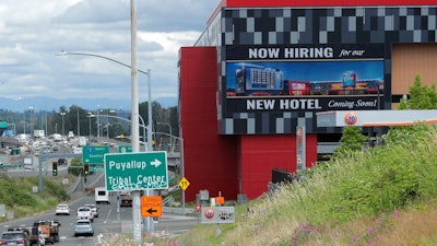 In this July 9, 2020, file photo, a large video display reads 'Now hiring for our new hotel coming soon!,' at the new Emerald Queen Casino, which is open, and owned by the Puyallup Tribe of Indians, in Tacoma, Wash. The United States added 1.8 million jobs in July, a pullback from the gains of May and June and evidence that the resurgent coronavirus has weakened hiring and the economic rebound.