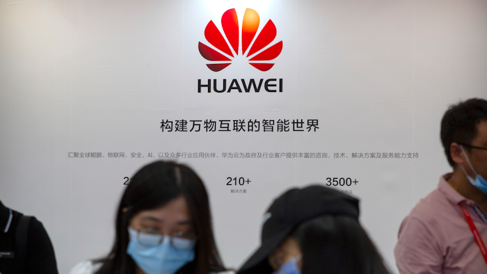 Visitors wearing face masks to protect against the coronavirus stand at a booth for Chinese technology firm Huawei at the China International Fair for Trade in Services (CIFTIS) in Beijing.
