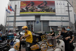 Residents wearing mask to protect themselves from contracting the coronavirus pass by a Chinese military propaganda display in Beijing.