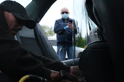 Luis Hidalgo, wearing face mask, watches as Joel Rios installs a plastic barrier in his car in the Bronx, New York, May 6, 2020.