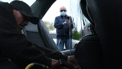 Luis Hidalgo, wearing face mask, watches as Joel Rios installs a plastic barrier in his car in the Bronx, New York, May 6, 2020.