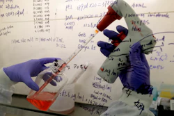 In this July 30 photo, Kai Hu, a research associate transfers medium to cells, in the laboratory at Imperial College in London. Imperial College is working on the development of a COVID-19 vaccine.