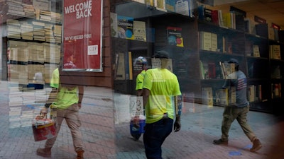 Workers are reflected in a window of a bookstore on Monday, Sept. 28 in the Harvard Square neighborhood of Cambridge, Mass.
