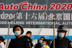 Security guards wearing masks and armed with restrainers stand guard at the entrance to the Auto China 2020 show in Beijing, China on Saturday, Sept. 26, 2020. The auto show, the first major in-person sales event for any industry since the coronavirus pandemic began, opens Saturday in a sign the ruling Communist Party is confident China has contained the disease. Still, automakers face intensive anti-virus controls including quarantines for visitors from abroad and curbs on crowd sizes at an event that usually is packed shoulder-to-shoulder with spectators.